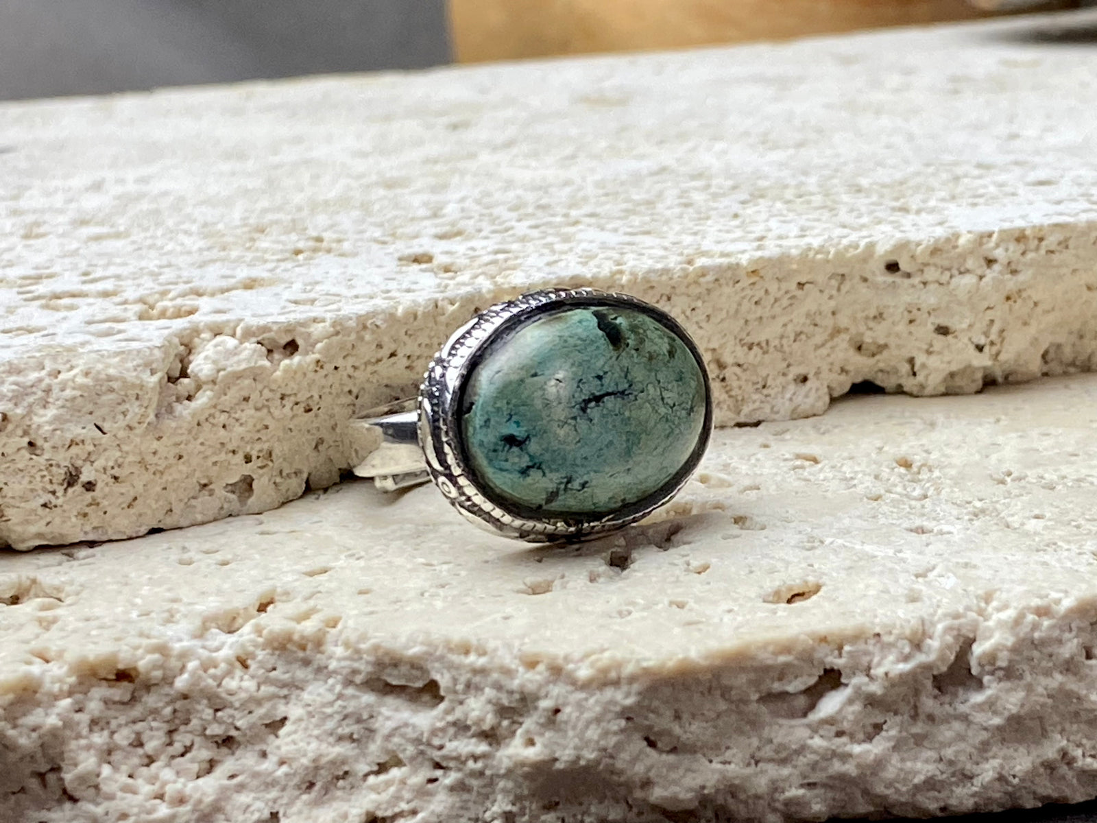 This simple ring features a large antique cabochon turquoise stone, set in a simple patterned silver bezel, with an adjustable ring band. As is the case with many of the rings we are currently buying, the stone is old and has been reset into a new silver band.  Measurements:  Ring face 2 x 1.5 cm Inner diameter 16.5 mm | Size 6 , however the adjustable band will fit any finger sized 5 -7