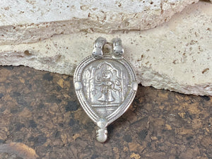 This amulet depicts Durga within the framework of the yoni leaf shape. High grade silver. Early 20th century or older. The double bail has an original wrap of cotton cord over it to protect it from further wear. Wear to the bail is evident but remains sturdy.  Measurements: height 5.5 cm including bail, width 3.4 cm