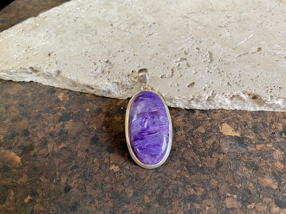 This lustrous charoite pendant is set off by a sterling silver bezel, topped by a bail that’s large enough to accommodate a thick chain or cord. A stunning piece of purple charoite with deep colour.  Measurements: 5.2 cm (2 in) height including bail, 2.2 cm (0.75 in) at widest point 