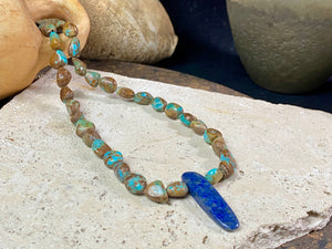 Our necklace is crafted from Tibetan turquoise with a central hand carved pendant of lapis lazuli. Finished with sterling silver beads and hook clasp. These beautiful natural stones range in colour from blue to blue-green. Length 42 cm