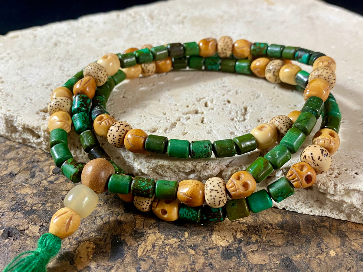 Our luxurious Buddhist mala contains 108 beads and has a beautifully organic look and feel. It's made from dark green turquoise beads, skull carved yak bone beads and lotus root beads, all finished with a sandalwood guru bead and a yak horn bead. Finished with a dark green tassel.