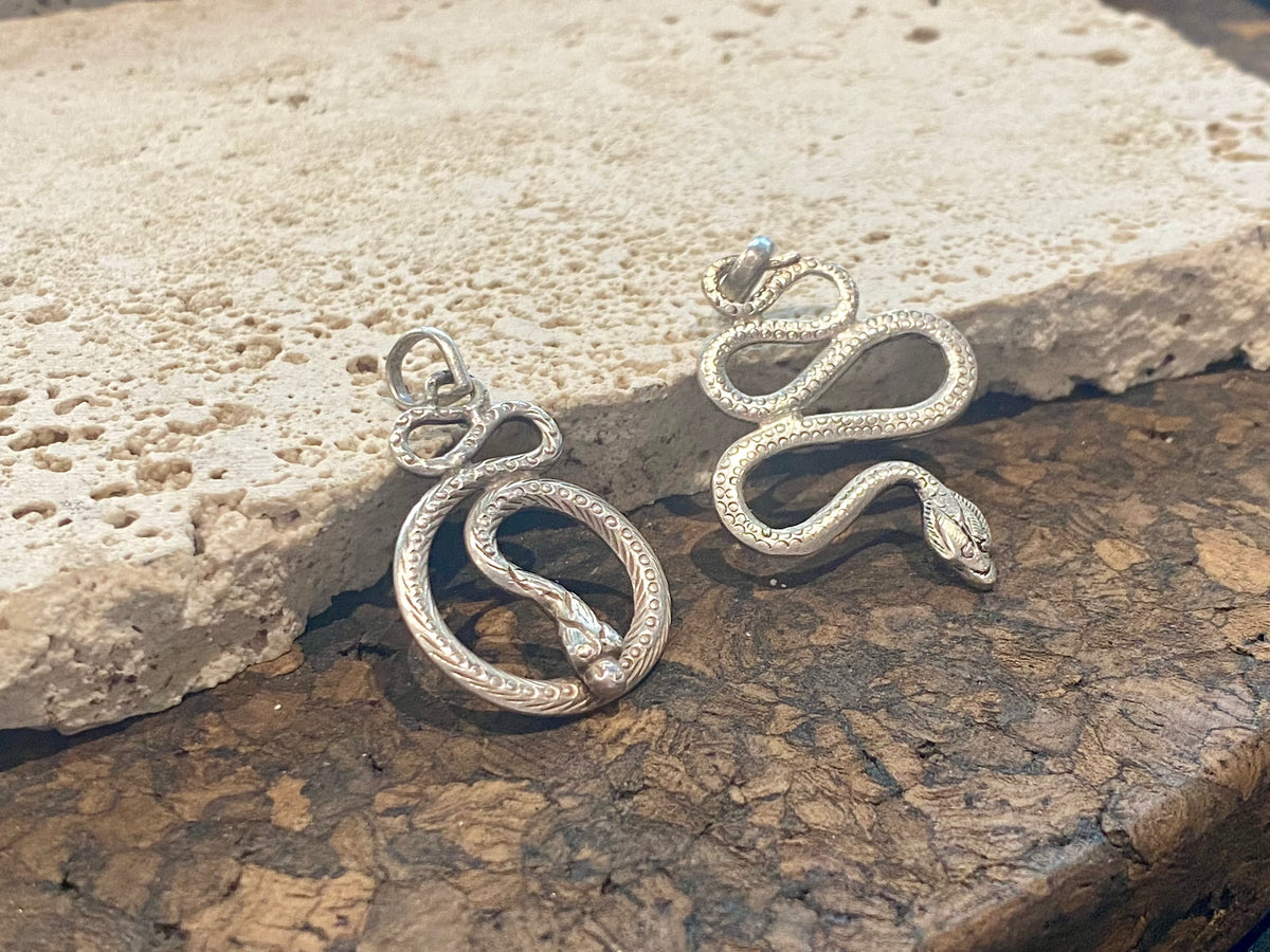 Hand cast snake pendants. Two styles. Sterling silver. Set with a wide bail capable of taking a sizeable chain or cord. Our unisex snake pendants are from Nepal.&nbsp;
