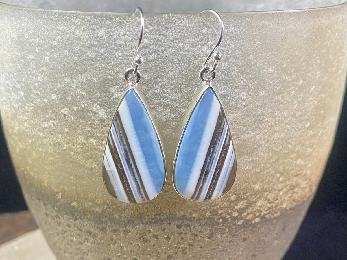 Our stunning earrings feature perfectly matched banded blue opal stones set in sterling silver bezels. Finished with sterling silver hooks.   