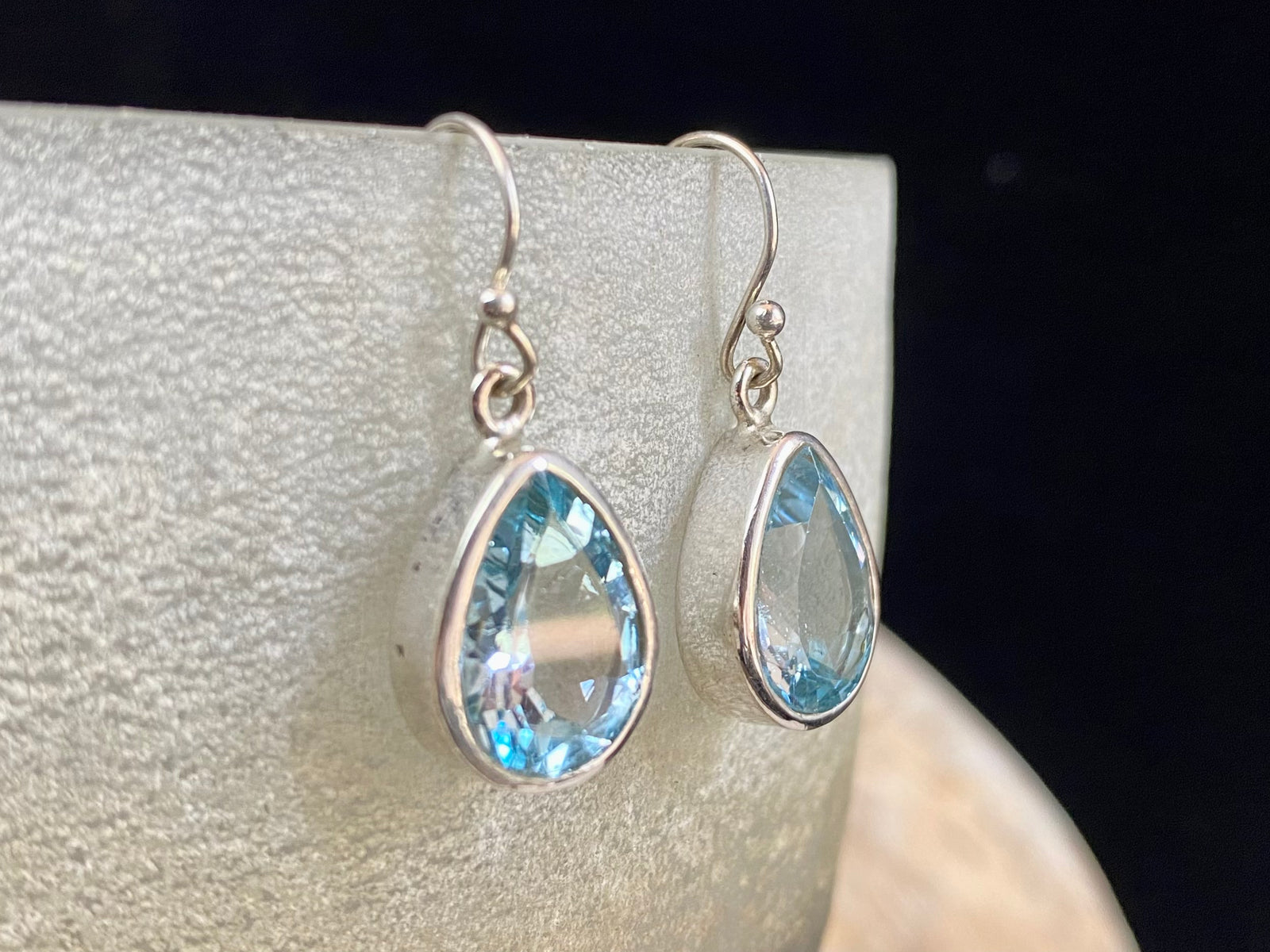 Blue topaz earrings. Deep teardrop cut stones are set in simple silver surrounds and finished with a shepherd hook. The topazes are facet cut to display their excellent quality and sparkle. Measurements: 3 cm height including hook, width 1.1 cm at widest point