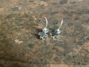 Tiny cross earrings. The body of the earring is made from a non-tarnishing white metal indistinguishable from silver, while the hooks are sterling silver. Lightweight and very easy to wear. Measurements: drop including hook 1.8 cm