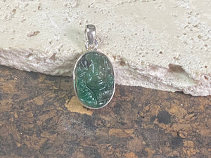 Hand carved from a single high quality translucent emerald and set in a silver surround with silver bail, this oval pendant features a beautifully detailed image of Ganesh.  Height including bail 3.1 cm, width 1.4 cm