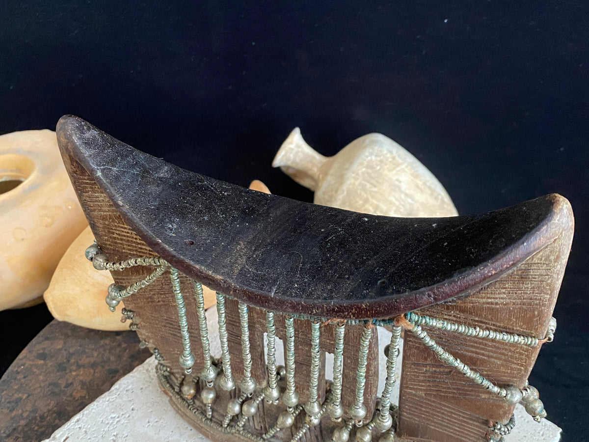 Kambatta wood headrest, Ethiopia. Early 1900's. Heavily carved and beaded. Dark patina and smooth wear on this piece are appropriate to its age. Measurements: height 16 cm (7"), width 18 cm