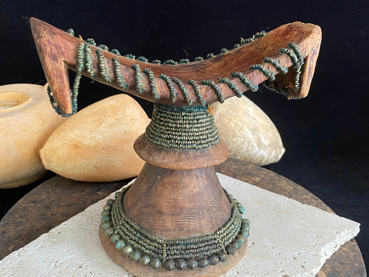 Very old Oromo wooden headrest from Ethiopia. Carved from a single piece of wood, heavily beaded with green oxidation. Pre 1950. The patina and wear on this piece are appropriate to its age.  Measurements: height 16 cm, width 18 cm