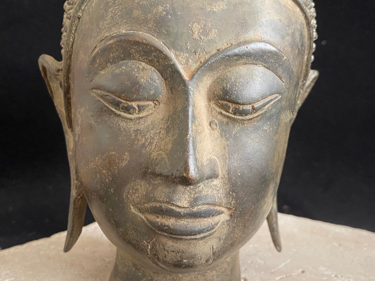 Thai Buddha head. Serene expression, hair topped with the flamed Ushnisha. Sukhothai style, bronze, mid 20th century. A softly contoured face with the bow shaped lips, prominent ears, arched eyebrows and aristocratic features typical of this style of work. Measurements: height 25 cm, width 11 cm