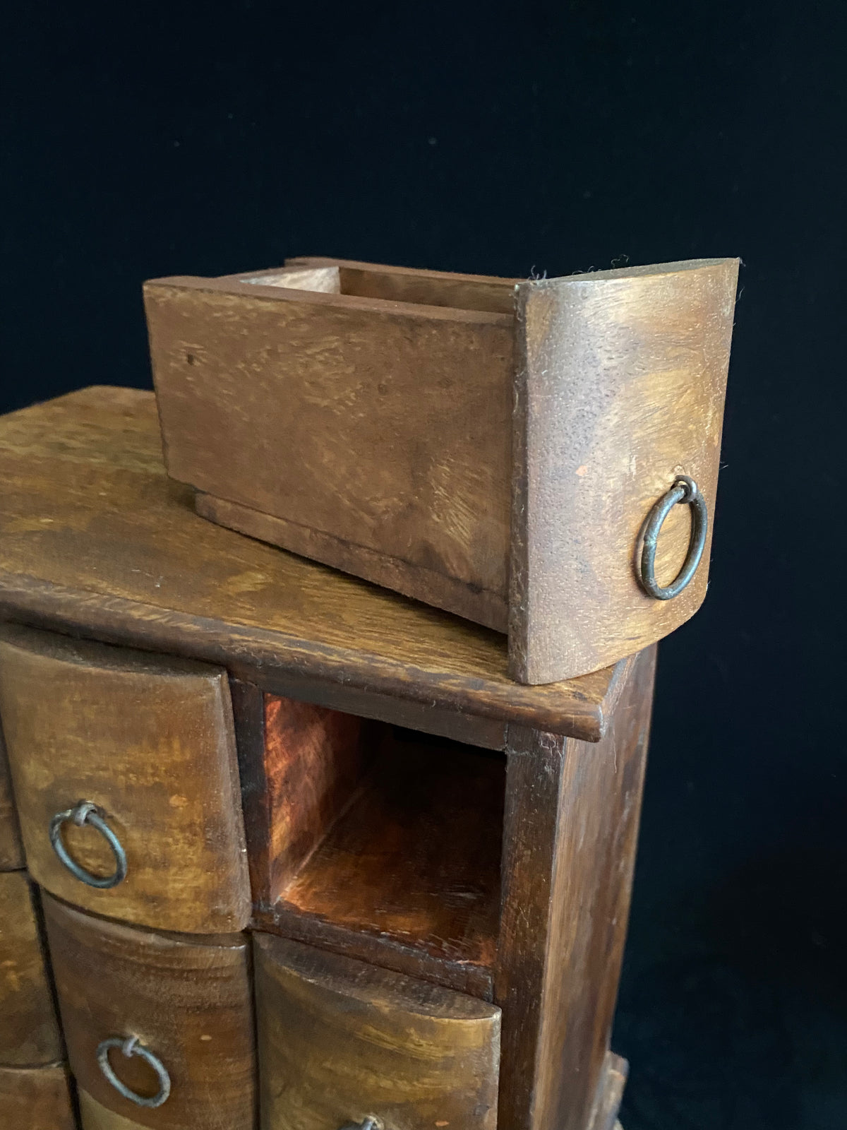 Simple curved face nine drawer cabinet trinket box. Made from solid Indian rosewood with iron rings as handles.  From Rajasthan, India. Made from Indian hard wood.  Height 28 cm, width 24.5 cm, depth 15.5 cm