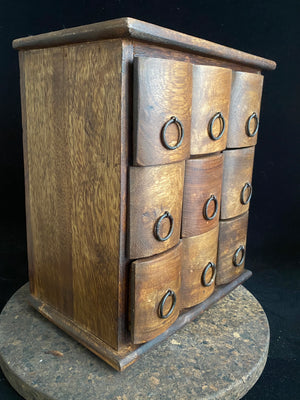 Simple curved face nine drawer cabinet trinket box. Made from solid Indian rosewood with iron rings as handles.  From Rajasthan, India. Made from Indian hard wood.  Height 28 cm, width 24.5 cm, depth 15.5 cm