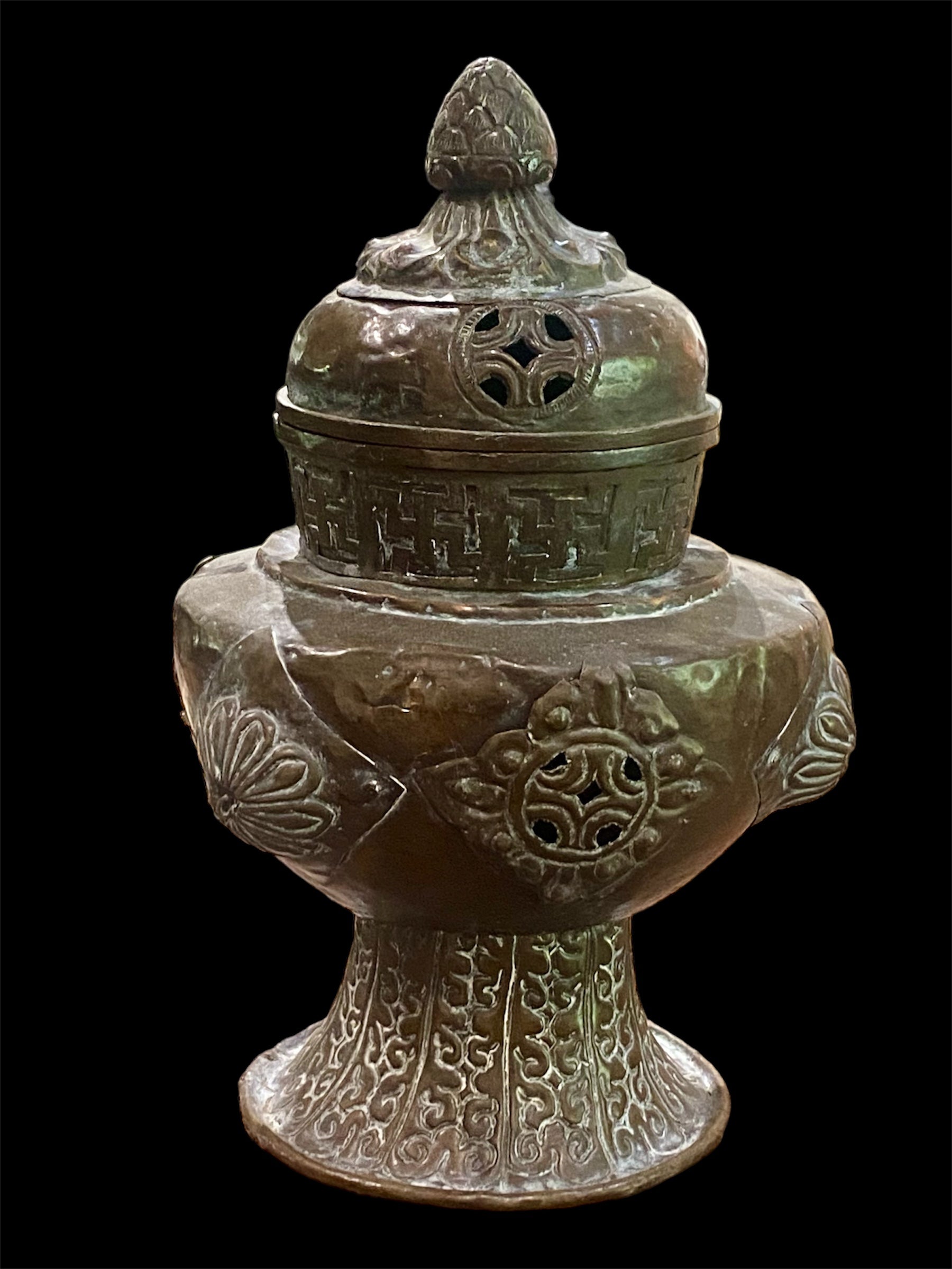Handmade large incense burner. Pierced & footed pot with lid and inner tin to hold incense. Topped with lotus bud, ringed with viswa vajras, lotus buds, cloud spandrels and a frieze of swastikas. Hand beaten copper, mid 20th century. Collected by Bernard Heaphy in a village near Mount Everest. 31 cm h x 17 cm diameter
