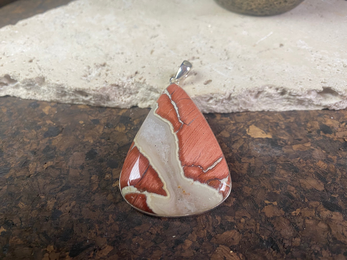 A unique pendant carved from a single piece of jasper intertwined with moonstone. A sterling silver bezel and generous bail completes this statement pendant. Open at the back to allow the stone to touch the skin. Measurements: height 6.8 cm including bail (2.75"), width 4 cm at widest point