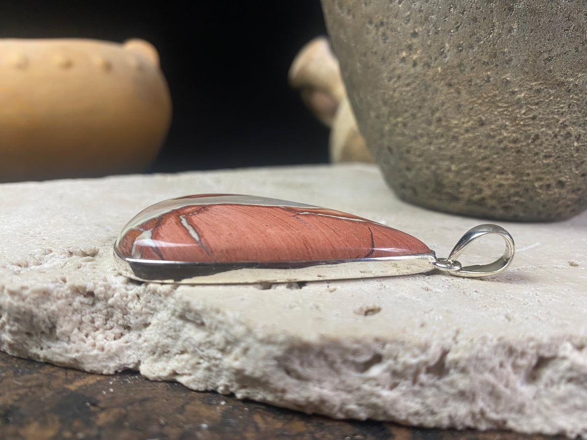 A unique pendant carved from a single piece of jasper intertwined with moonstone. A sterling silver bezel and generous bail completes this statement pendant. Open at the back to allow the stone to touch the skin. Measurements: height 6.8 cm including bail (2.75"), width 4 cm at widest point