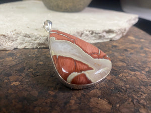 A unique pendant carved from a single piece of jasper intertwined with moonstone. A sterling silver bezel and generous bail completes this statement pendant. Open at the back to allow the stone to touch the skin. Measurements: height 6.8 cm including bail (2.75"), width 4 cm at widest point
