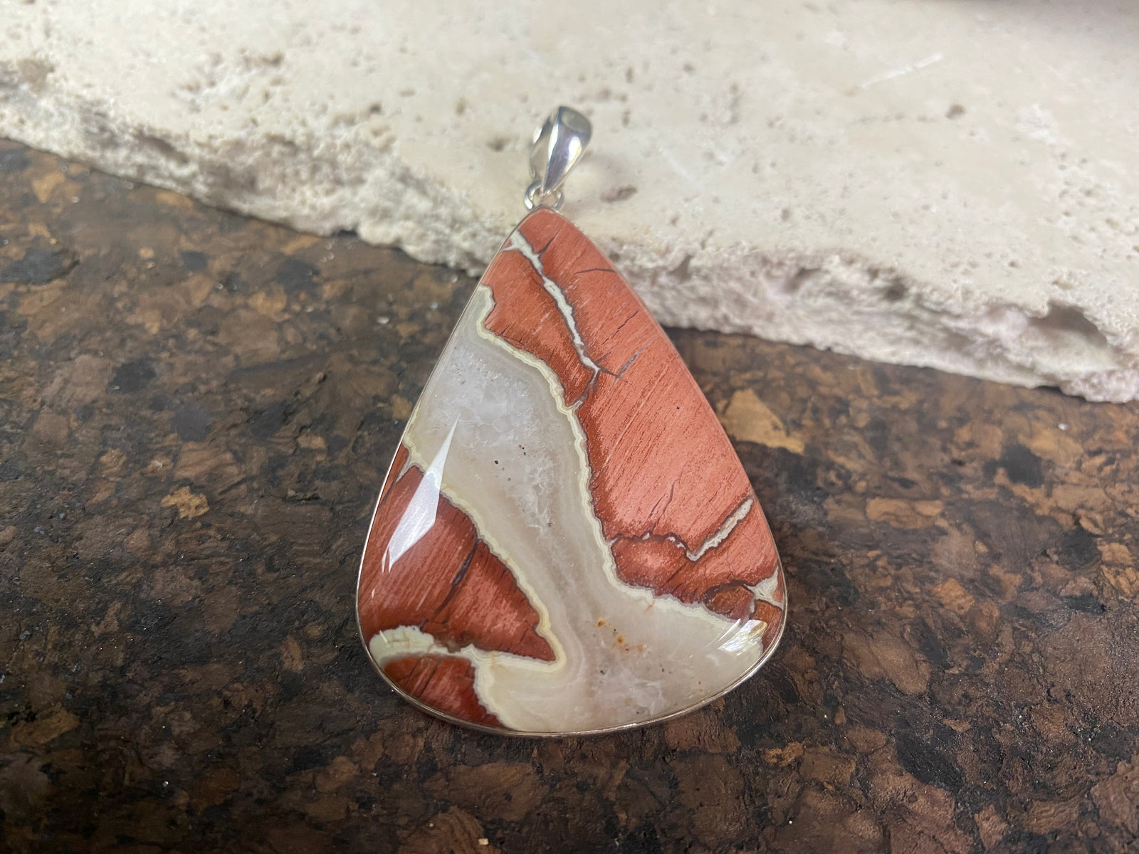 A unique pendant carved from a single piece of jasper intertwined with moonstone. A sterling silver bezel and generous bail completes this statement pendant. Open at the back to allow the stone to touch the skin. Measurements: height 6.8 cm including bail (2.75"), width 4 cm at widest point