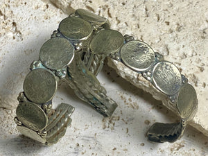 Antique silver cuffs consist of Indian half rupee coins welded to an inner cuff of silver. Two coins date to 1918, and are 91.7% silver. Older or younger coins vary but all half rupees contain min 50% silver. The cuffs are rigid and can only be altered slightly. Inside width 8 cm, height 1.8 cm.