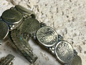 Antique silver cuffs consist of Indian half rupee coins welded to an inner cuff of silver. Two coins date to 1918, and are 91.7% silver. Older or younger coins vary but all half rupees contain min 50% silver. The cuffs are rigid and can only be altered slightly. Inside width 8 cm, height 1.8 cm.