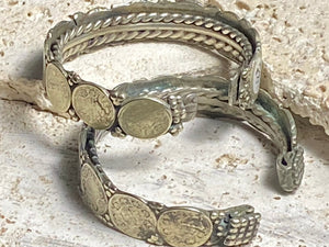 Antique silver cuffs consist of Indian half rupee coins welded to an inner cuff of silver. Two coins date to 1918, and are 91.7% silver. Older or younger coins vary but all half rupees contain min 50% silver. The cuffs are rigid and can only be altered slightly. Inside width 8 cm, height 1.8 cm.