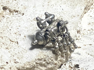 High grade silver amulet with fused ends, early 20th century, from northern India. The decoration is unusual, with a bar connecting the bails and a set of silver dangles fused together. Measurements: length 3.1 cm, diameter 1.5 cm, height including dangles 3 cm