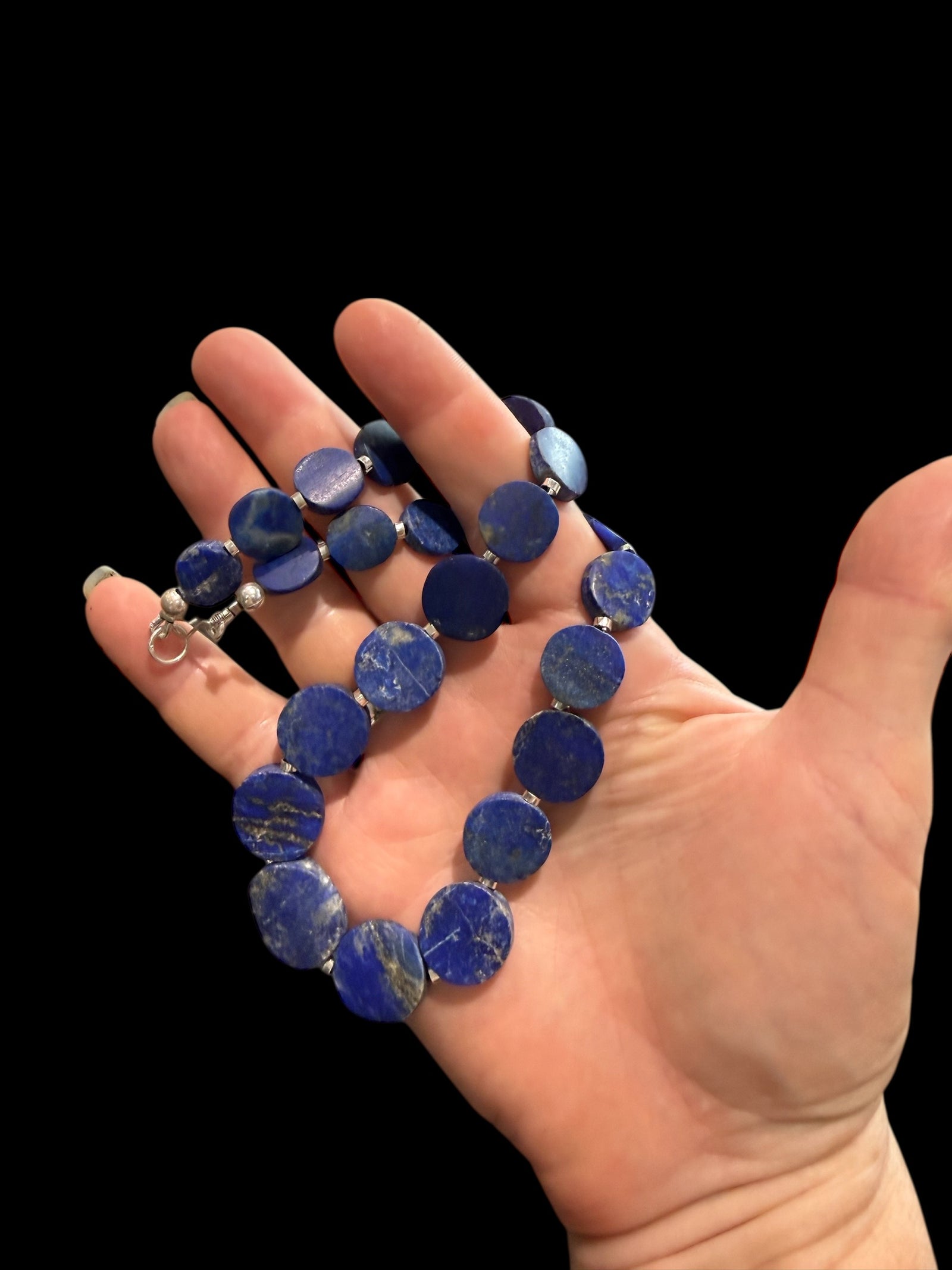 Natural lapis lazuli flat disk beads, colour matched and graduated, with sterling silver spacer beads and a sterling silver clasp. Length 43 cm