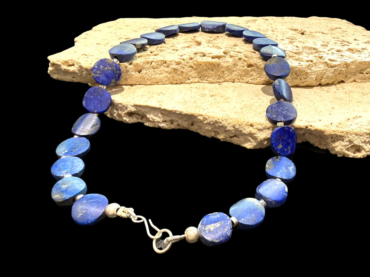 Natural lapis lazuli flat disk beads, colour matched and graduated, with sterling silver spacer beads and a sterling silver clasp. Length 43 cm
