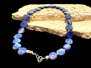 Natural lapis lazuli flat disk beads, colour matched and graduated, with sterling silver spacer beads and a sterling silver clasp. Length 43 cm