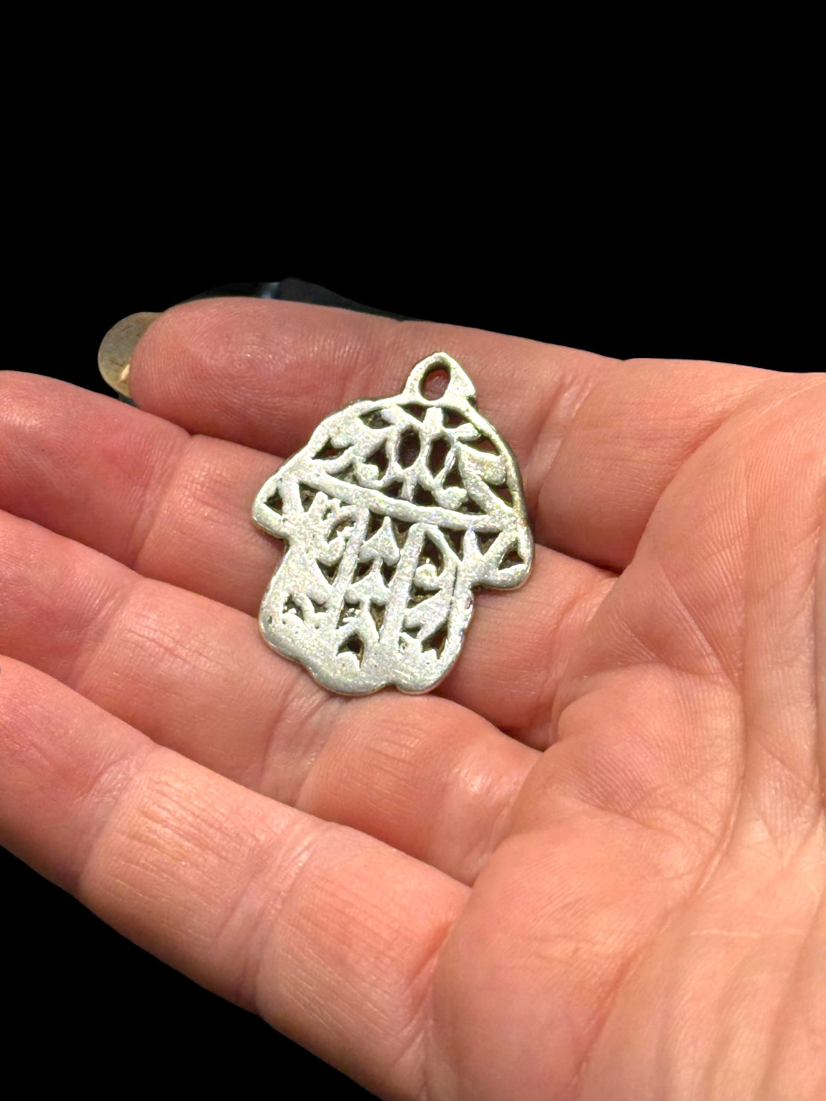 Antique Tunisian silver hamsa amulet pendant. Cast openwork decoration, rounded outline, softened detail consistent with wear. Height 3.5 cm, width 2.6 cm