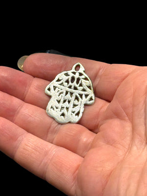 Antique Tunisian silver hamsa amulet pendant. Cast openwork decoration, rounded outline, softened detail consistent with wear. Height 3.5 cm, width 2.6 cm