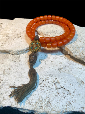 Mala of 54 beads. Resin beads highlighted with a brass pendant featuring the viswa vajra & Om mantra & Buddha bead in Vietnamese sandalwood, 62 cm total length.