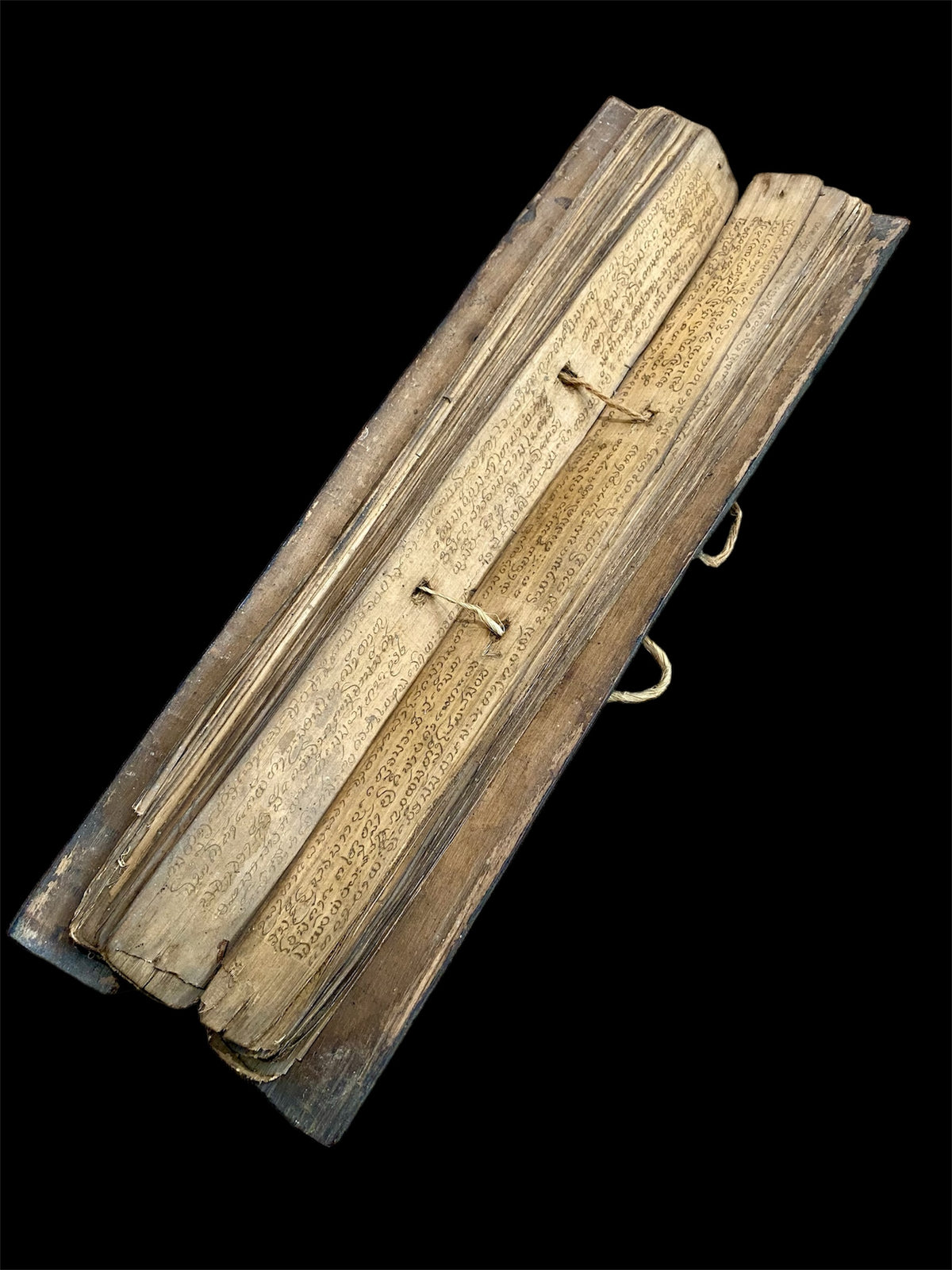 Sinhalese palm (ola) leaf book, ca. early 20th century CE. South Asia. Religious text from a Hindu-Buddhist monastery. Contains 60 leaves bound by two cords between a pair of wood slat covers. Measurements: Length 56 cm (22") x height 7.5 cm (3") x width 4.5 cm (1.75")