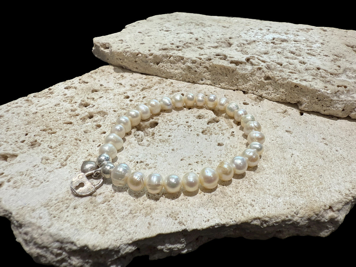 Freshwater pearl bracelet with sterling silver bead & charm detailing. Elasticised stringing for a seamless look.

Measurements: wrist circumference 16 - 17 cm.