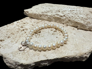 Freshwater pearl bracelet with sterling silver bead & charm detailing. Elasticised stringing for a seamless look.

Measurements: wrist circumference 16 - 17 cm.