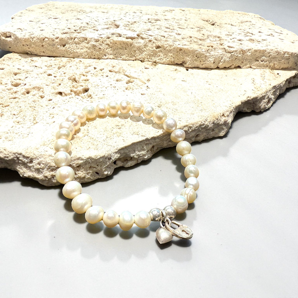 Freshwater pearl bracelet with sterling silver bead & charm detailing. Elasticised stringing for a seamless look.

Measurements: wrist circumference 16 - 17 cm.