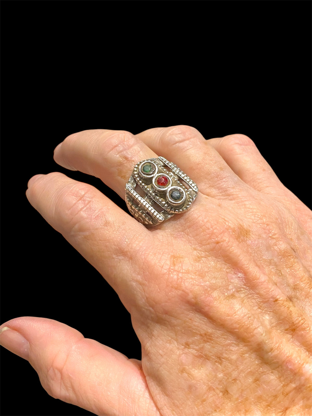 This unusual ring features three glass "gemstones" in a cutout design. High grade silver. Afghani, early 20th C. Face 2.5 cm height Sizing: 19.5 mm | Size 9.75