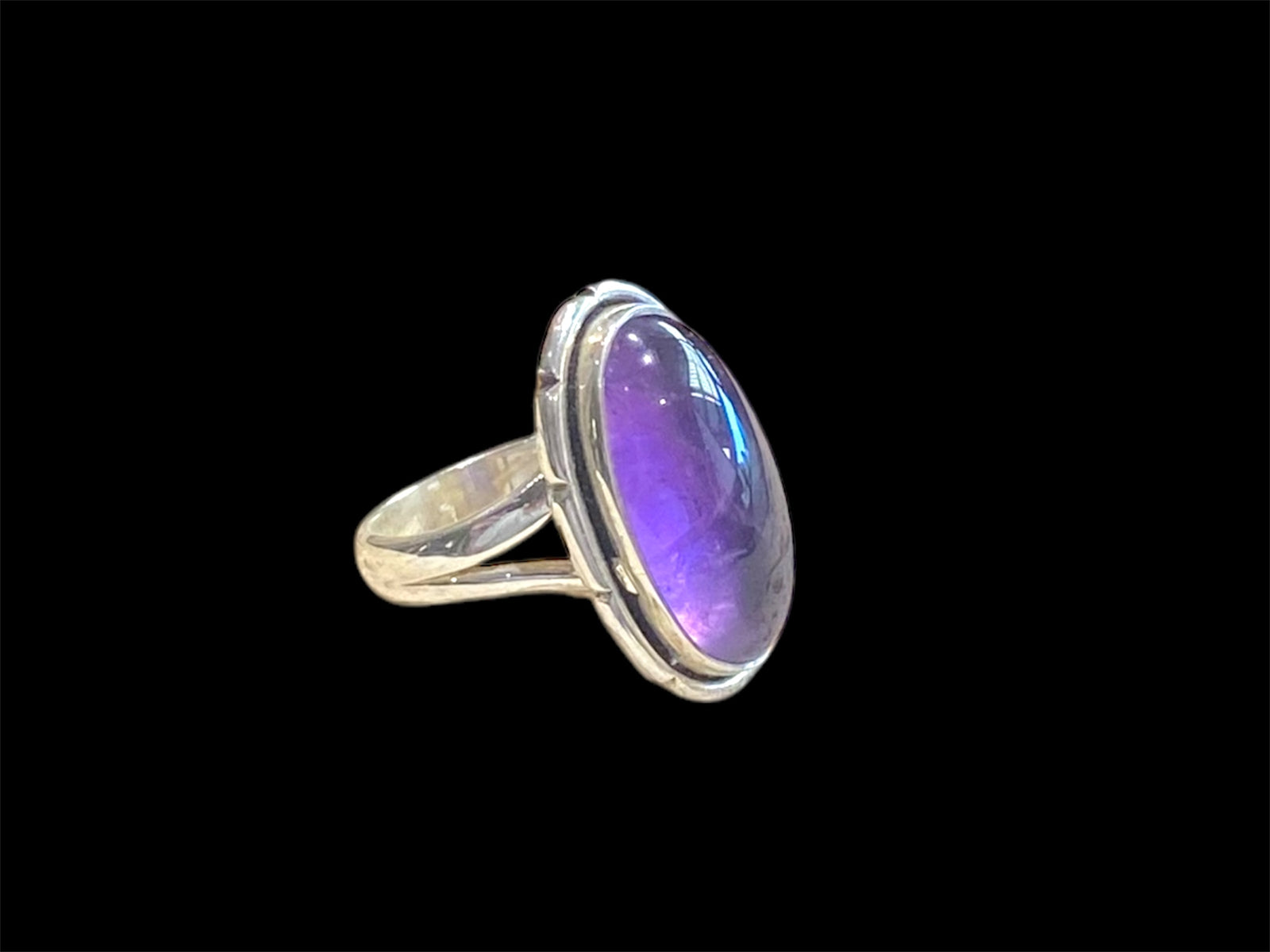 Elegant oval amethyst ring set in sterling silver. Open at the back to allow light to shine through, allowing the stone's natural beauty to shine through. Measurements: Face 2.4 x 1.4 cm Sizing: US Size 6 | 16.5 mm