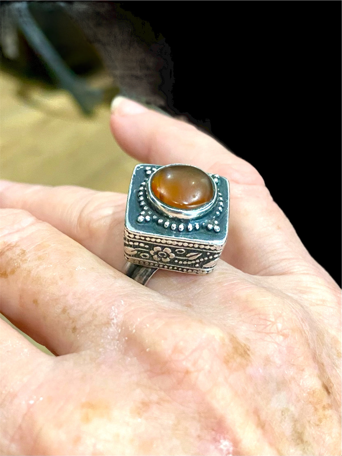 An unusual ring featuring a round carnelian stone set in a high box setting. Afghanistan, mid to late 20th century. Can be worn by either men or women. Measurements: Ring face 2.5 x 2.5, cm, height 1.5 cm. This is an adjustable ring spanning sizes 7 - 8