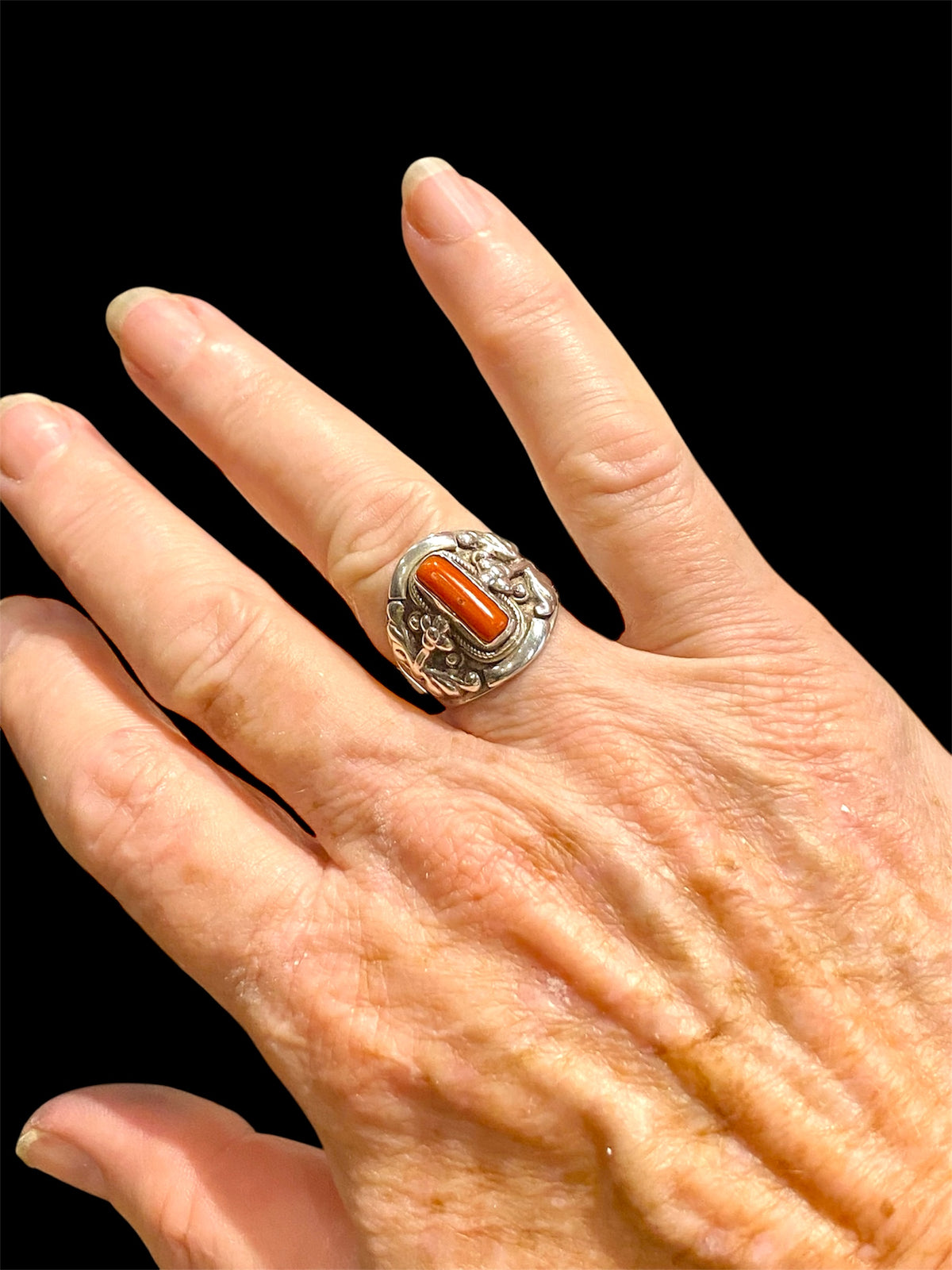 Beautifully detailed, petite ring set with a cabochon cut coral stone. Sterling silver. Handmade in Nepal. Measurements: Length of face 2 cm. Size 7.25 | 17.75 mm
