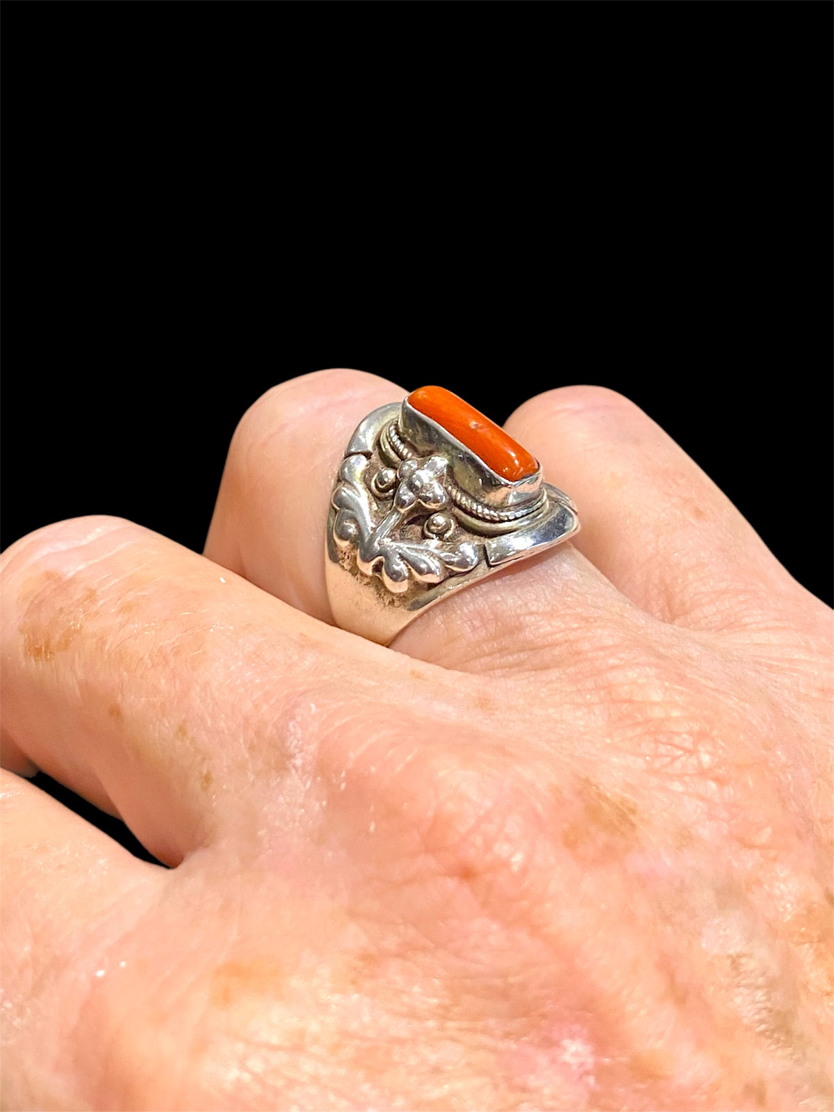 Beautifully detailed, petite ring set with a cabochon cut coral stone. Sterling silver. Handmade in Nepal. Measurements: Length of face 2 cm. Size 7.25 | 17.75 mm