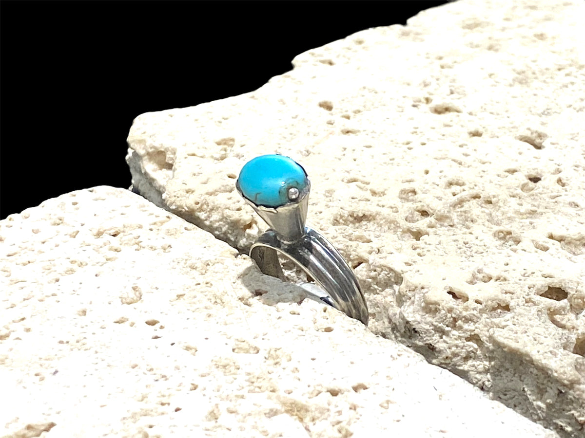 This unusual ring features an oval turquoise stone, set in a very high conical mount over a slender band. The turquoise stone is of excellent quality and contains very little matrix. Central Asia. Circa 1930. Stone 1 x 0.8 cm. Size 7 | 17.5 mm