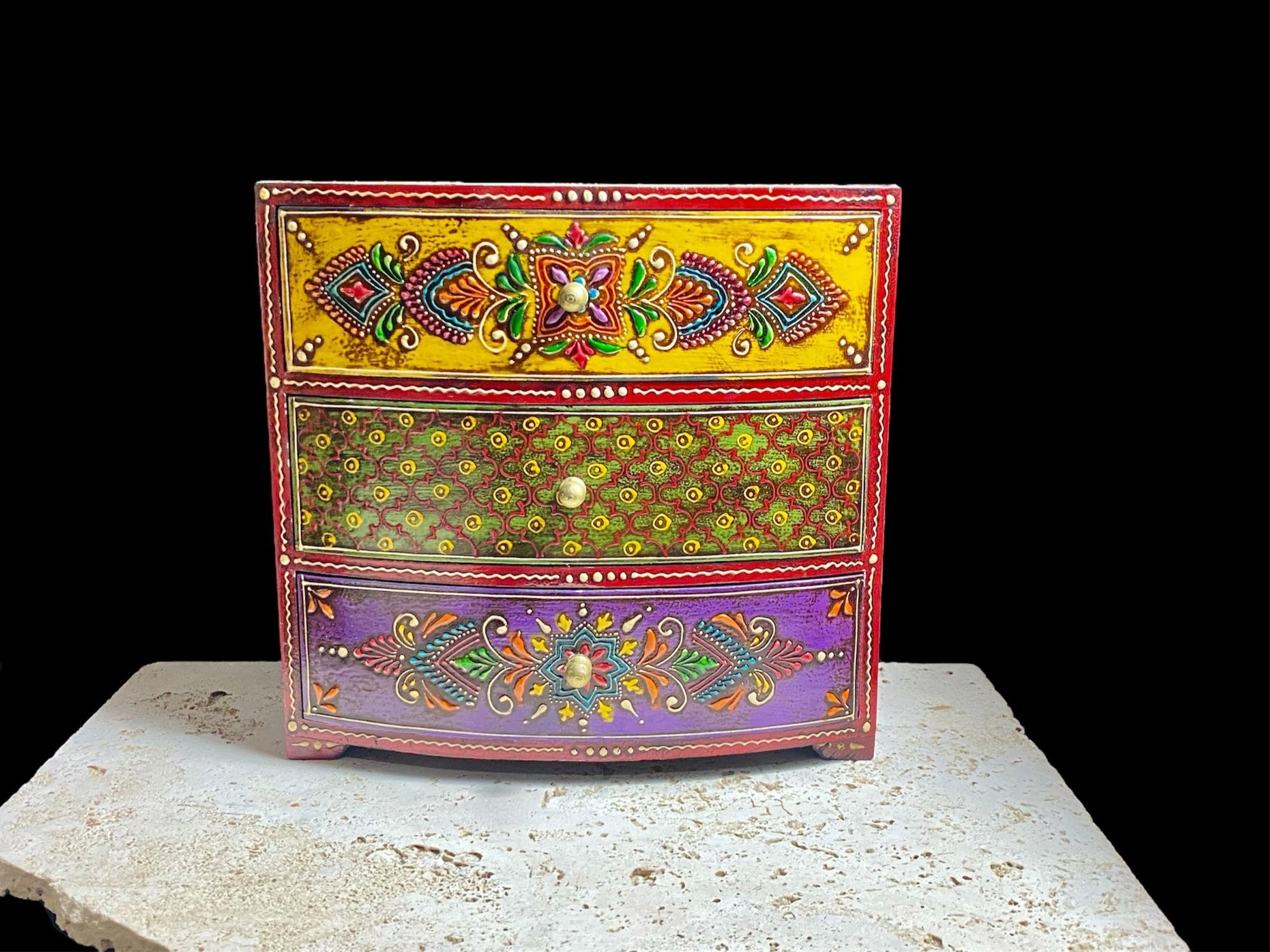 This brightly painted box features three spacious drawers, a curved front and small feet. Brass knobs as handles add a touch of elegance to our storage chest, perfect for holding everything from trinkets to jewellery and essential oils. From Rajasthan, India. Width 23.5, depth 13 cm, height 23 cm
