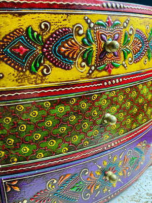 This brightly painted box features three spacious drawers, a curved front and small feet. Brass knobs as handles add a touch of elegance to our storage chest, perfect for holding everything from trinkets to jewellery and essential oils. From Rajasthan, India. Width 23.5, depth 13 cm, height 23 cm