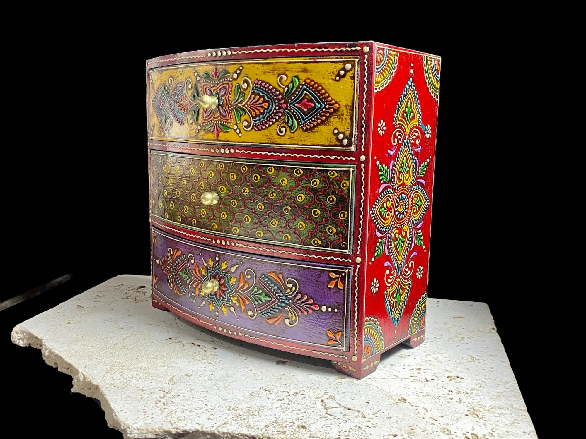 This brightly painted box features three spacious drawers, a curved front and small feet. Brass knobs as handles add a touch of elegance to our storage chest, perfect for holding everything from trinkets to jewellery and essential oils. From Rajasthan, India. Width 23.5, depth 13 cm, height 23 cm
