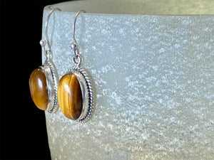 These classic oval earrings feature high quality, large cabochon cut oval tiger's eye stones set in a detailed sterling silver bezel.

Measurements: 3 cm (1.2”) length including hook