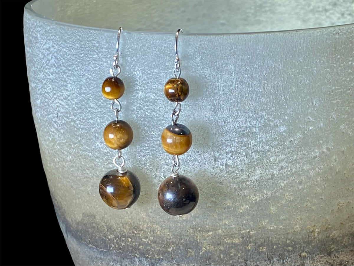 A simple, elegant earring consisting of three graduated drops of tigers eye, with sterling silver detailing and hooks.

Measurements: length 4.5 cm