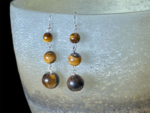 A simple, elegant earring consisting of three graduated drops of tigers eye, with sterling silver detailing and hooks.

Measurements: length 4.5 cm