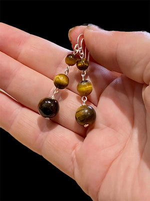 A simple, elegant earring consisting of three graduated drops of tigers eye, with sterling silver detailing and hooks.

Measurements: length 4.5 cm