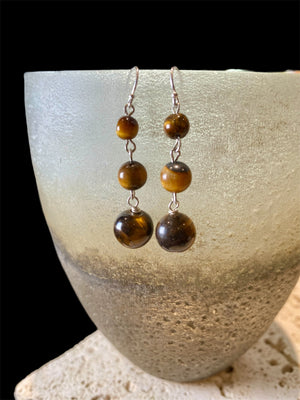 A simple, elegant earring consisting of three graduated drops of tigers eye, with sterling silver detailing and hooks.

Measurements: length 4.5 cm