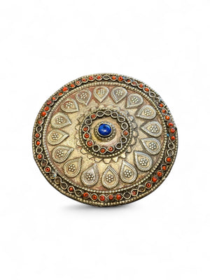 Turkoman pectoral pendant  (selpi guljaka). Applied leaf motifs, granulation and wire work set with ceramic beads (some of which are missing) and a central lapis cabochon. High grade silver. At the back is a soldered flat loop for attachment to the garment. Late 19th century. Diameter 9.5 cm