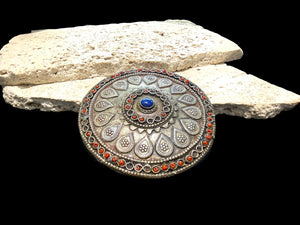 Turkoman pectoral pendant  (selpi guljaka). Applied leaf motifs, granulation and wire work set with ceramic beads (some of which are missing) and a central lapis cabochon. High grade silver. At the back is a soldered flat loop for attachment to the garment. Late 19th century. Diameter 9.5 cm
